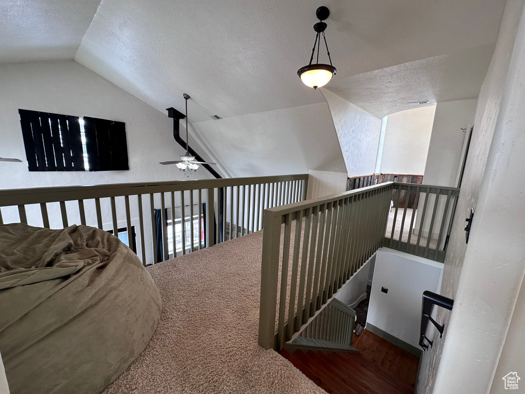 Stairs featuring lofted ceiling, carpet floors, a textured ceiling, and ceiling fan