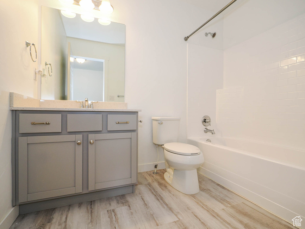 Full bathroom featuring hardwood / wood-style flooring, shower / bath combination, toilet, and vanity