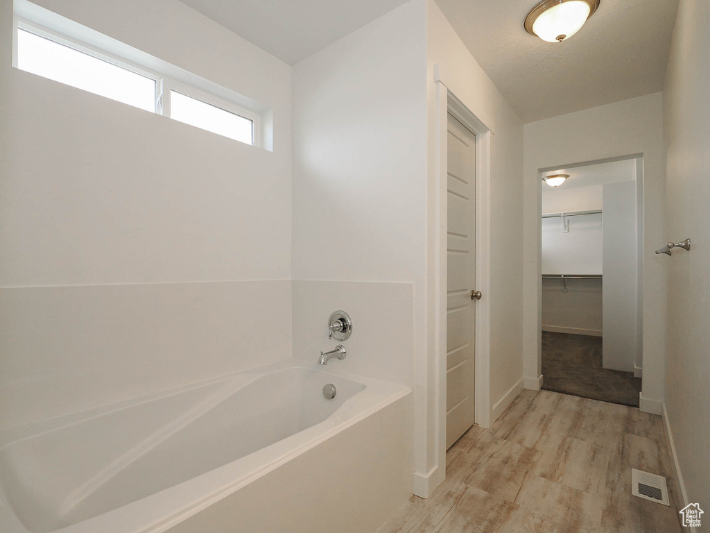 Bathroom featuring a bath to relax in and hardwood / wood-style flooring