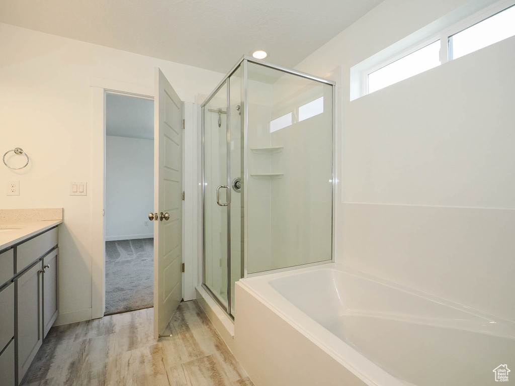 Bathroom with vanity, independent shower and bath, and hardwood / wood-style floors