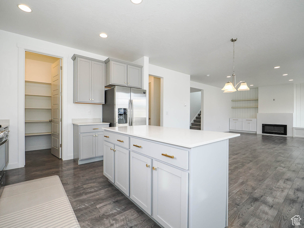 Kitchen with an inviting chandelier, dark hardwood / wood-style flooring, decorative light fixtures, a center island, and stainless steel refrigerator with ice dispenser