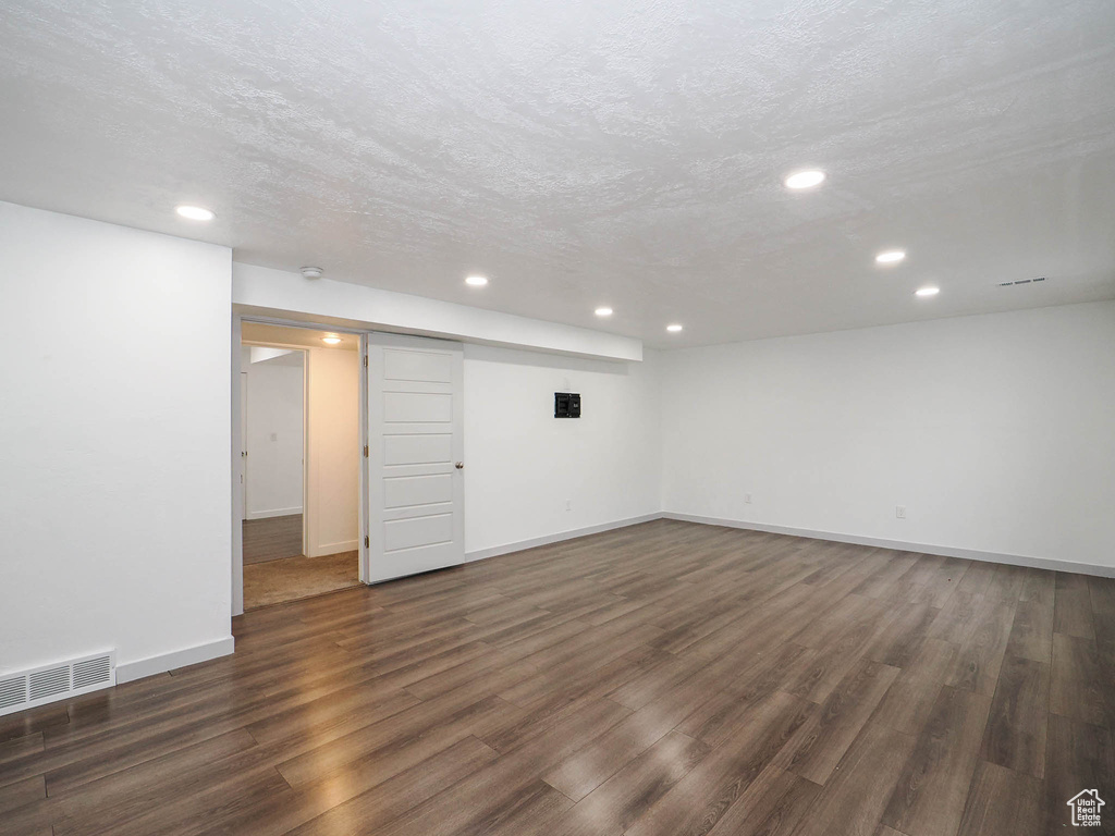 Basement with dark hardwood / wood-style flooring and a textured ceiling