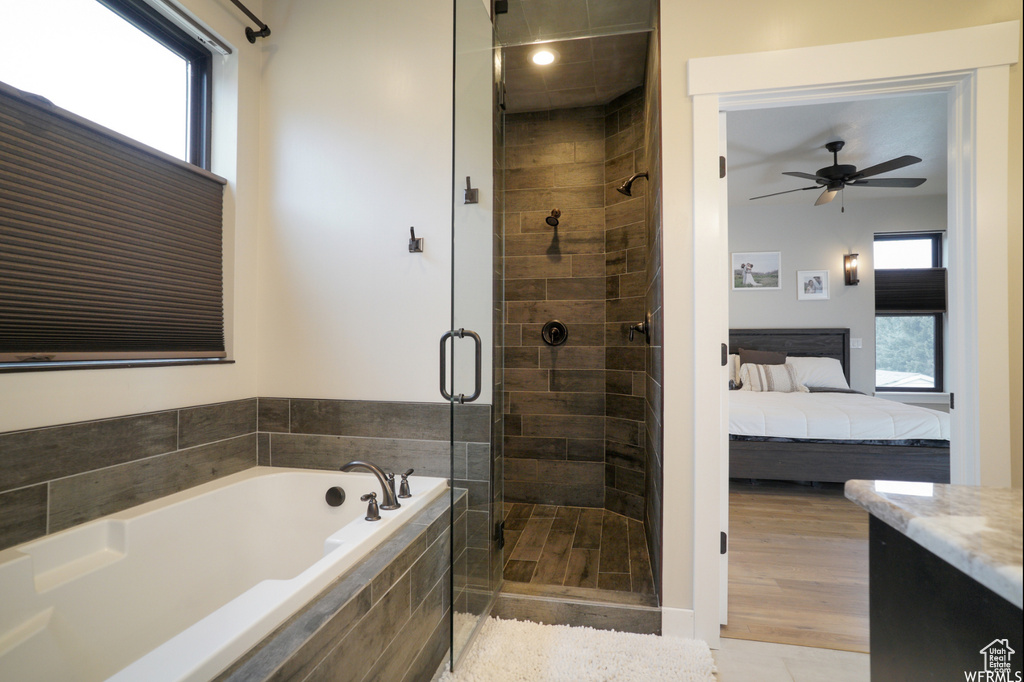 Bathroom with plenty of natural light, independent shower and bath, hardwood / wood-style floors, and ceiling fan