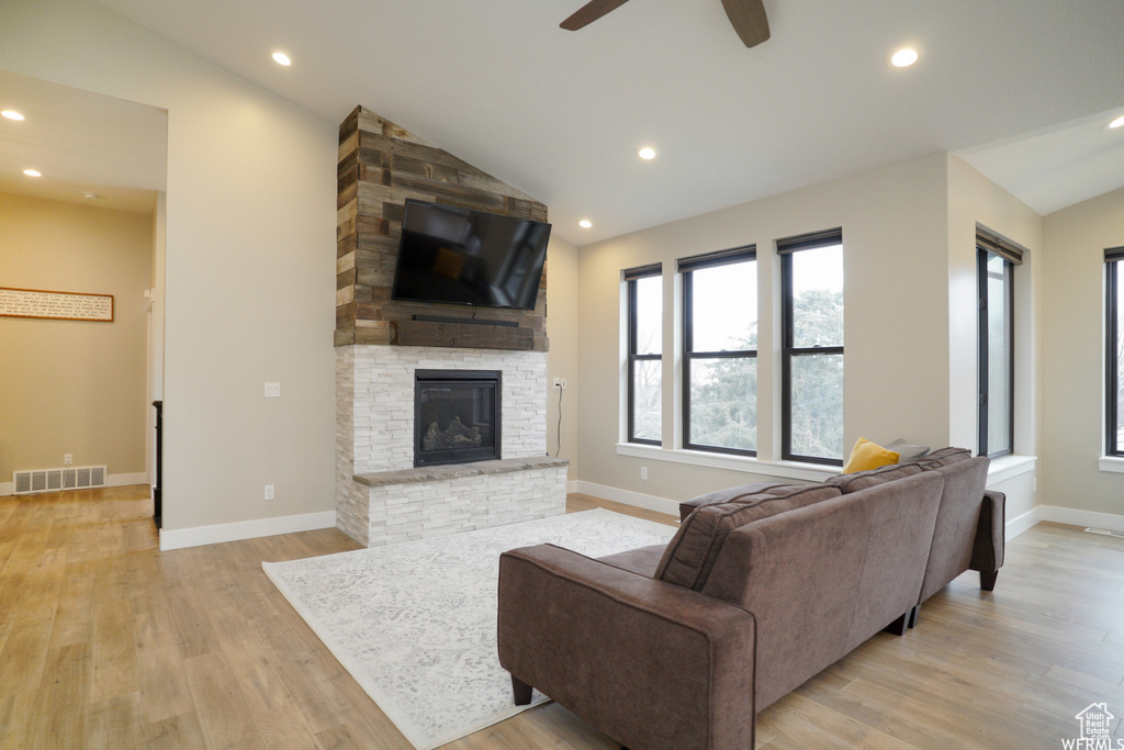Living room with light wood-type flooring, lofted ceiling, a fireplace, and ceiling fan