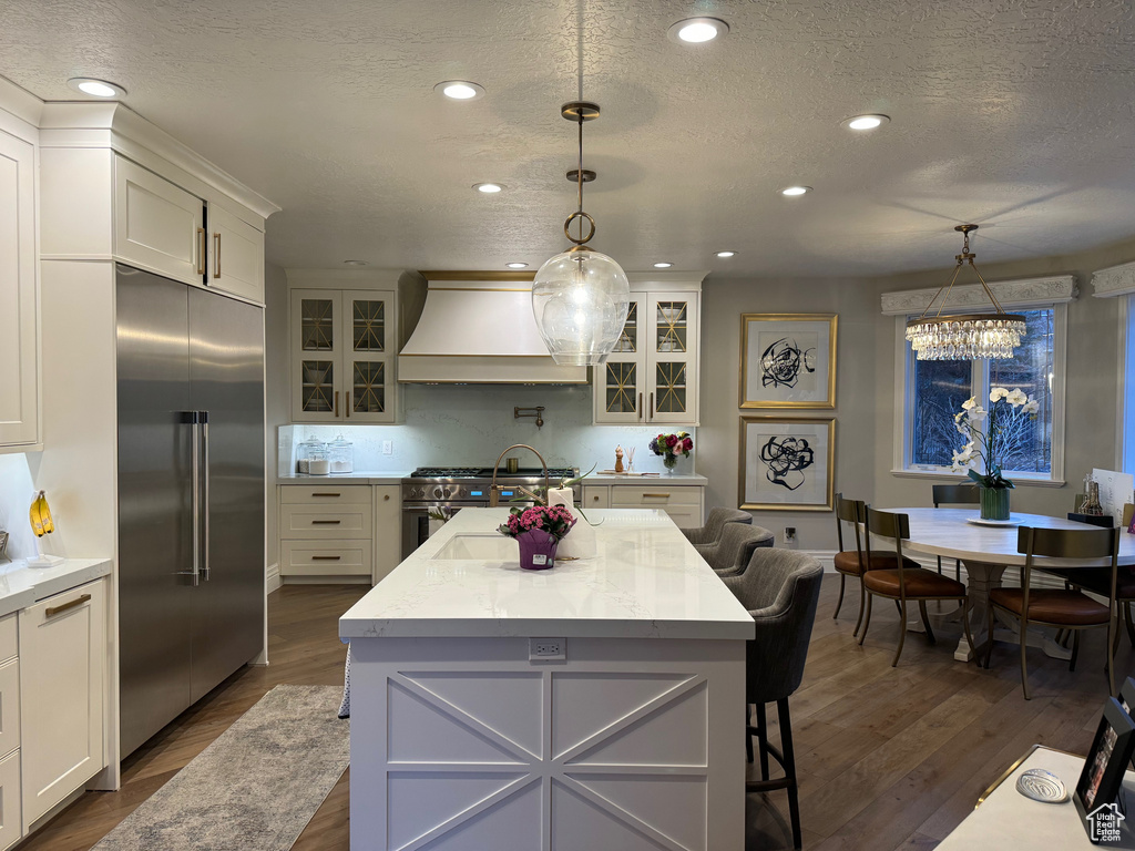 Kitchen featuring a notable chandelier, pendant lighting, custom range hood, and premium appliances