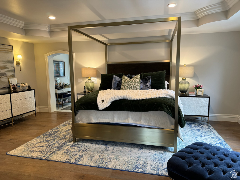 Bedroom featuring dark wood-type flooring, ornamental molding, and a tray ceiling