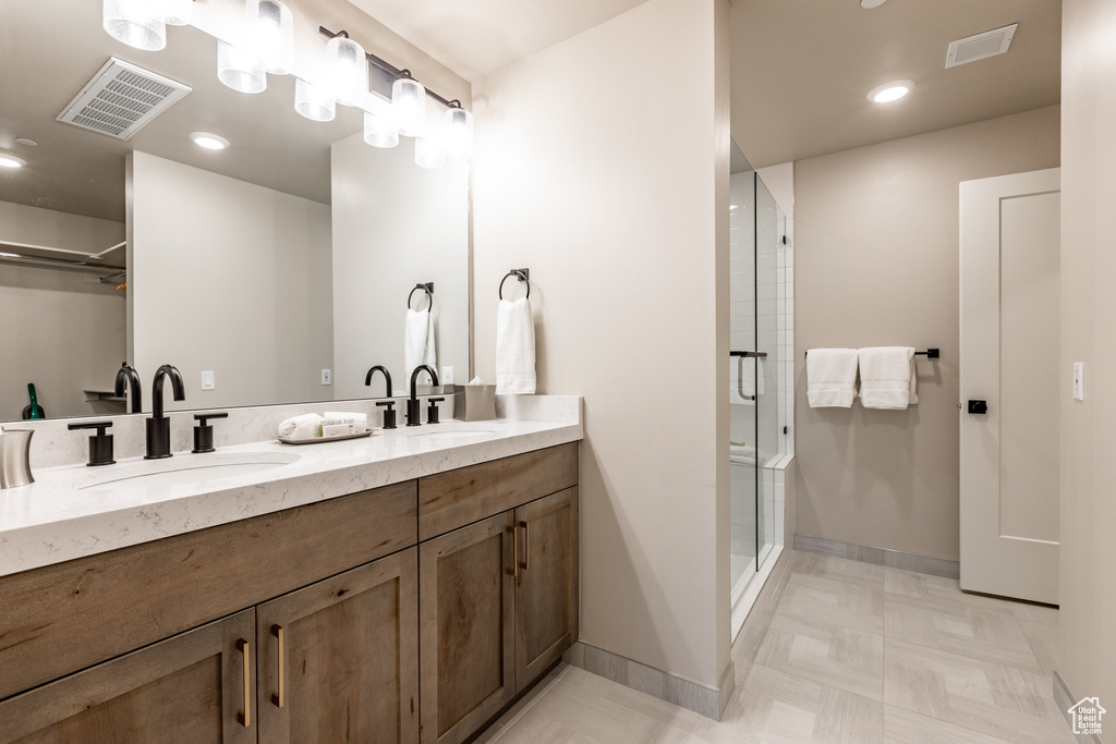 Bathroom with tile flooring, large vanity, dual sinks, and walk in shower