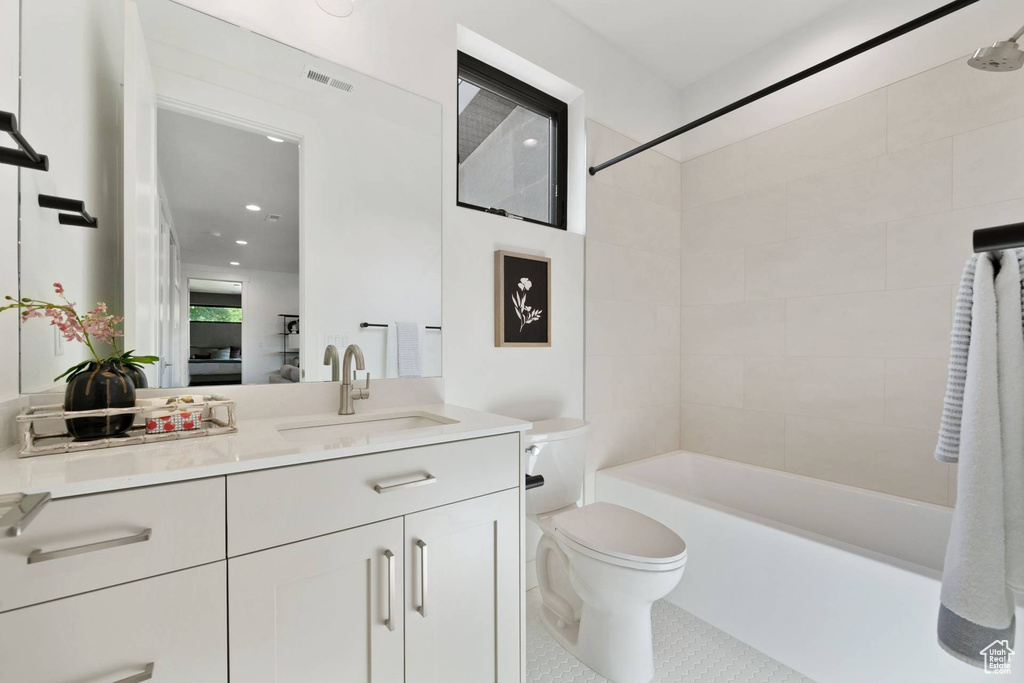 Full bathroom with vanity, toilet, tiled shower / bath combo, and tile floors