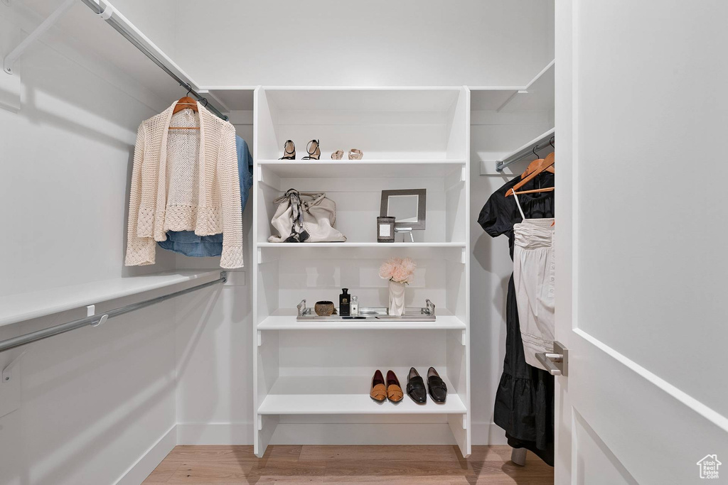 Walk in closet with light hardwood / wood-style floors