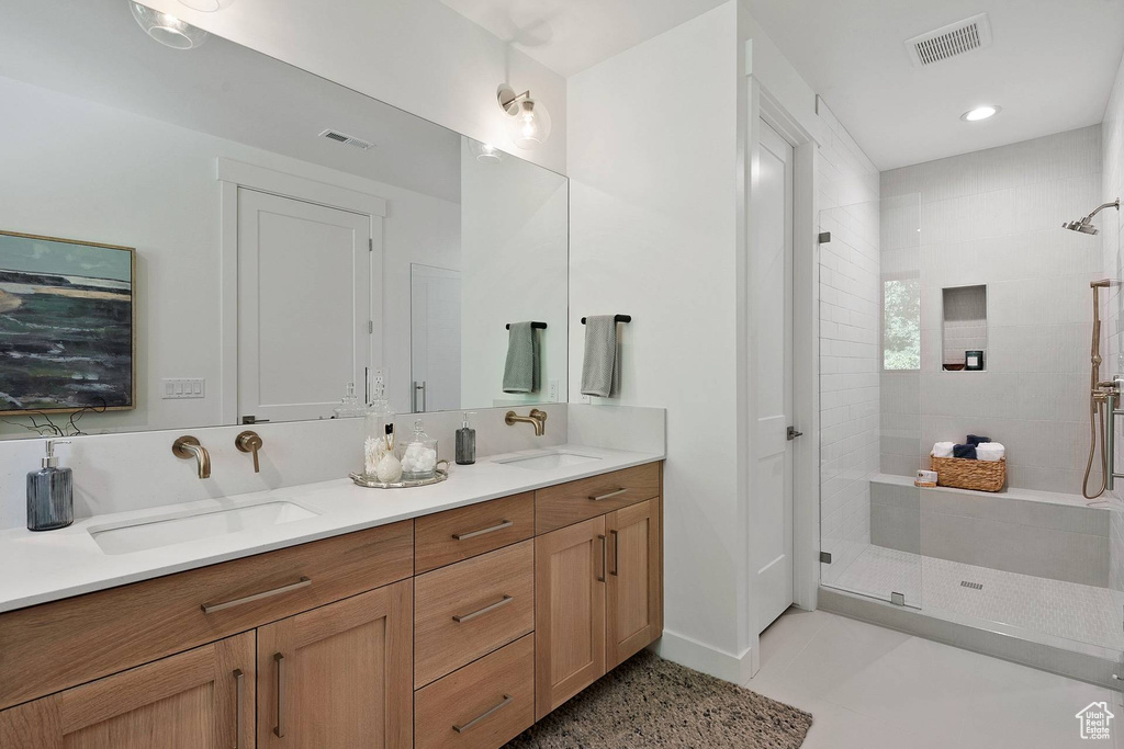 Bathroom featuring an enclosed shower, dual sinks, tile flooring, and vanity with extensive cabinet space