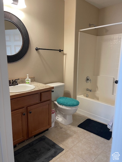 Full bathroom featuring toilet, vanity, tile floors, and tub / shower combination