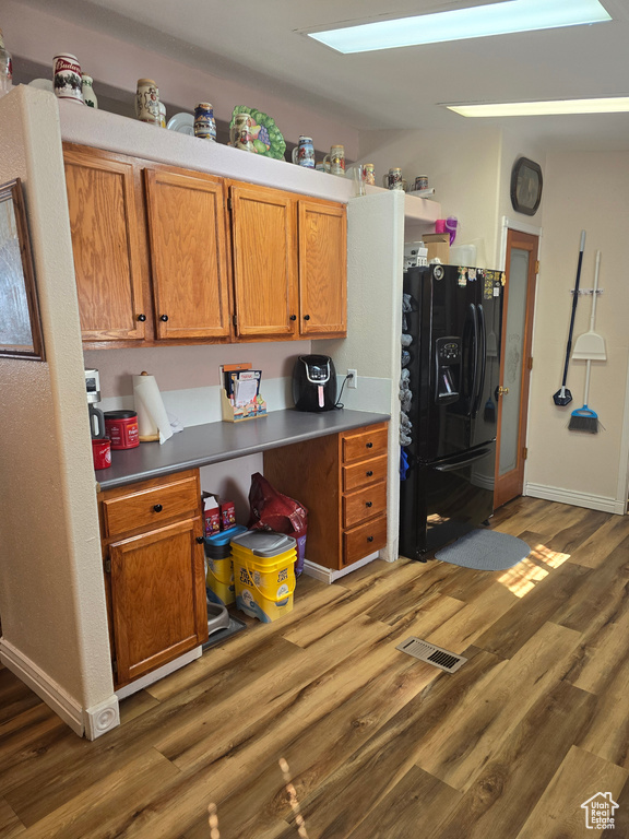 Kitchen with a skylight, black fridge, and dark wood-type flooring