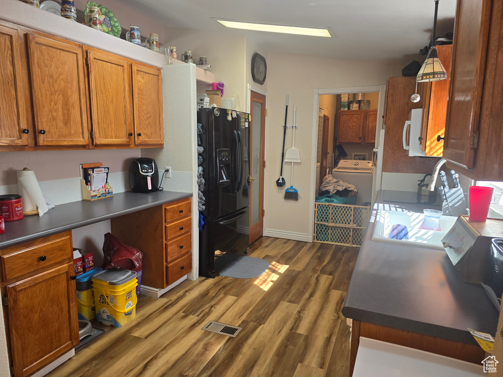Kitchen featuring decorative light fixtures, washer / clothes dryer, dark hardwood / wood-style floors, and black fridge with ice dispenser