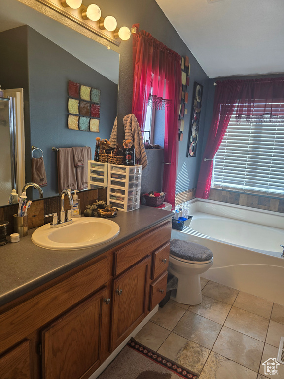Bathroom featuring vaulted ceiling, tile flooring, vanity with extensive cabinet space, a washtub, and toilet
