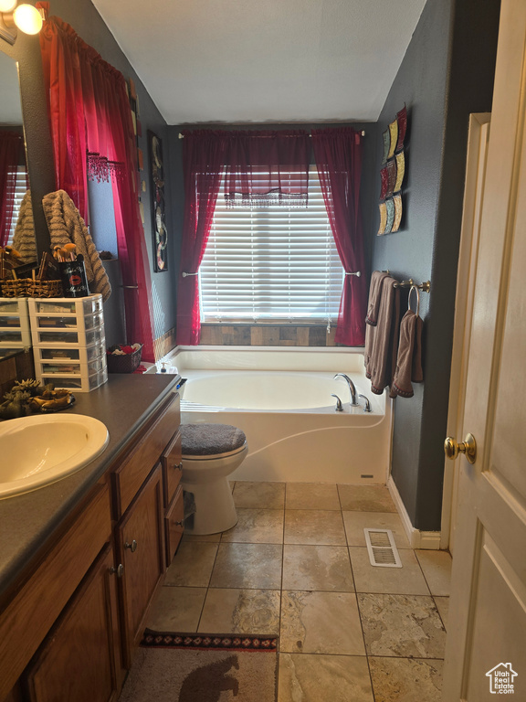 Bathroom featuring vanity, toilet, tile flooring, and a bath
