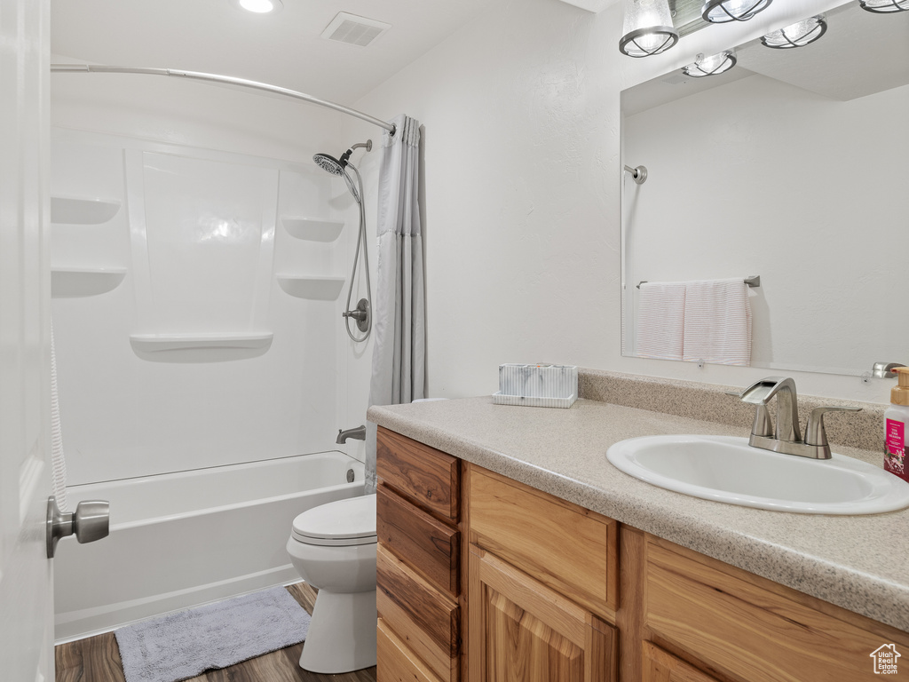 Full bathroom with shower / bath combo, toilet, vanity with extensive cabinet space, and hardwood / wood-style flooring