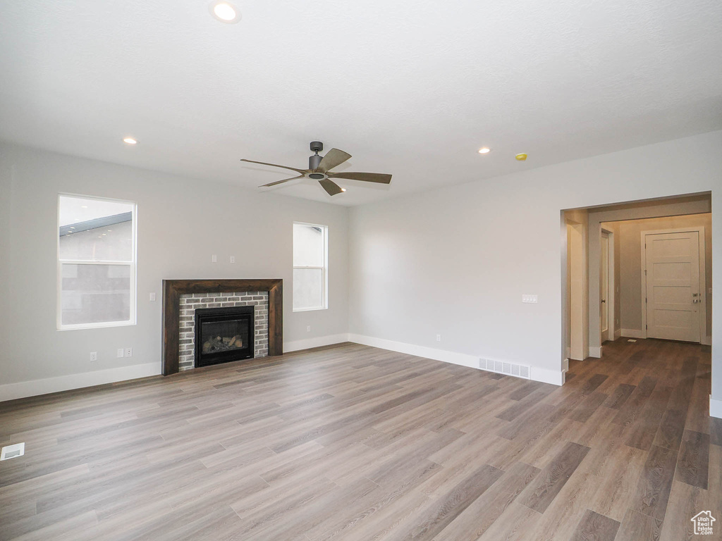 Unfurnished living room with a fireplace, light hardwood / wood-style flooring, and ceiling fan