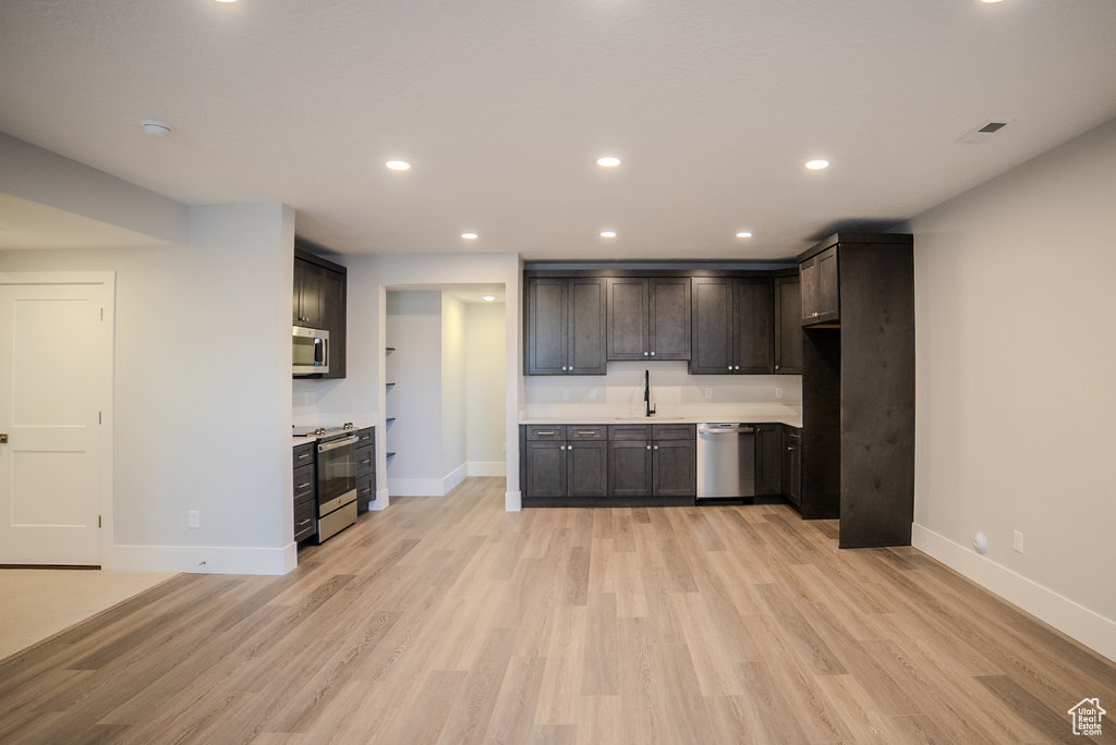 Kitchen featuring dark brown cabinets, stainless steel appliances, sink, and light hardwood / wood-style flooring