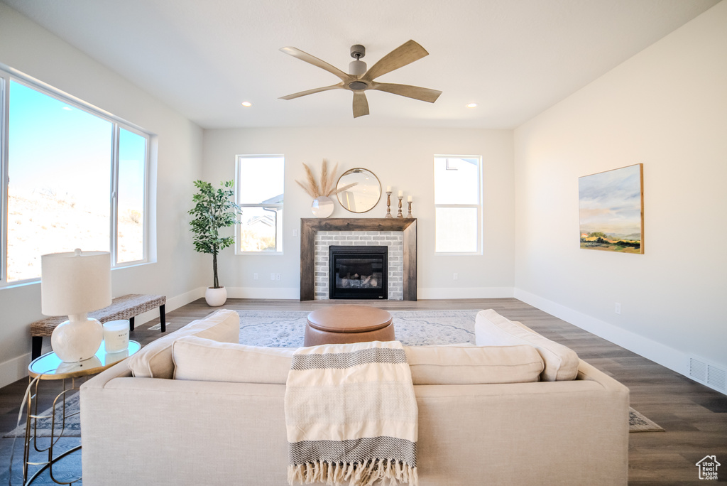 Living room with a fireplace, ceiling fan, hardwood / wood-style flooring, and a healthy amount of sunlight