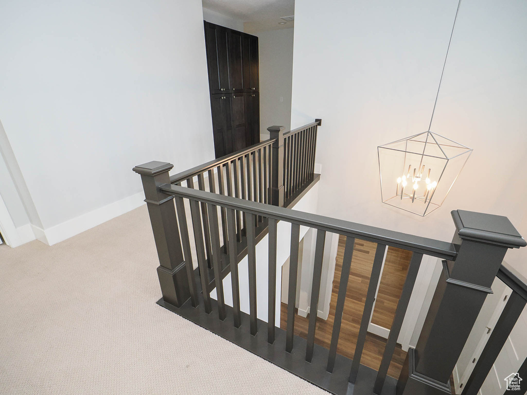 Stairway featuring an inviting chandelier, light carpet, and a high ceiling