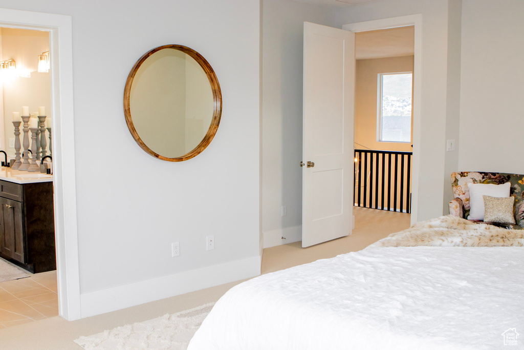 Bedroom featuring sink, ensuite bath, and light colored carpet