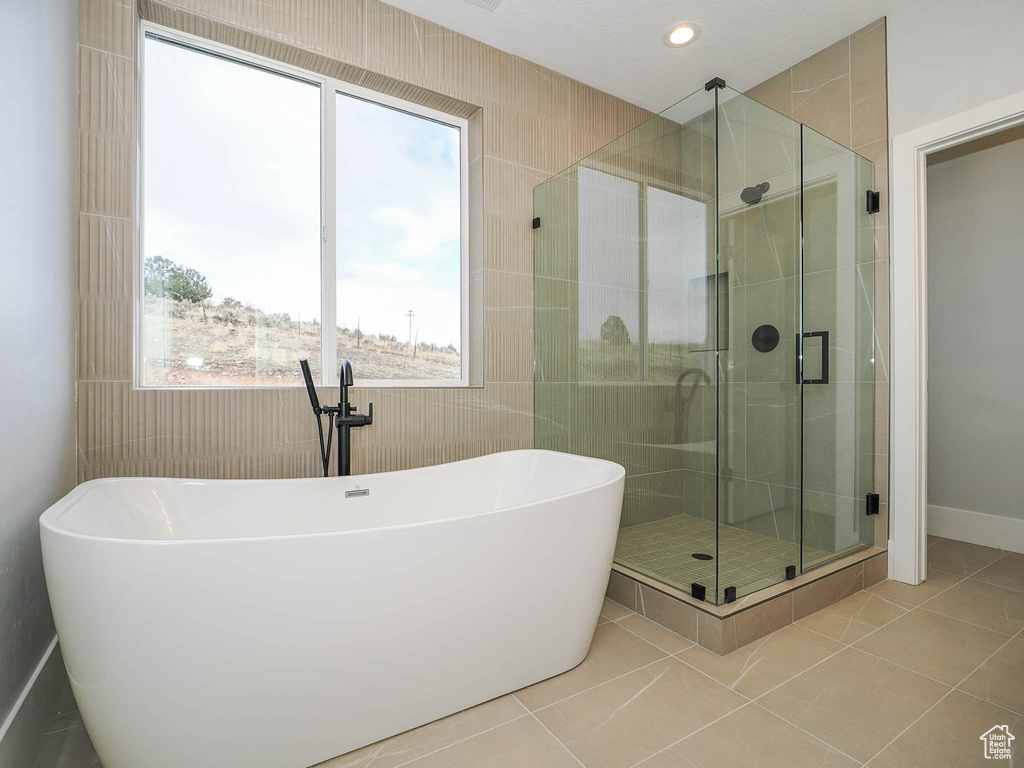 Bathroom with tile walls, tile flooring, and separate shower and tub