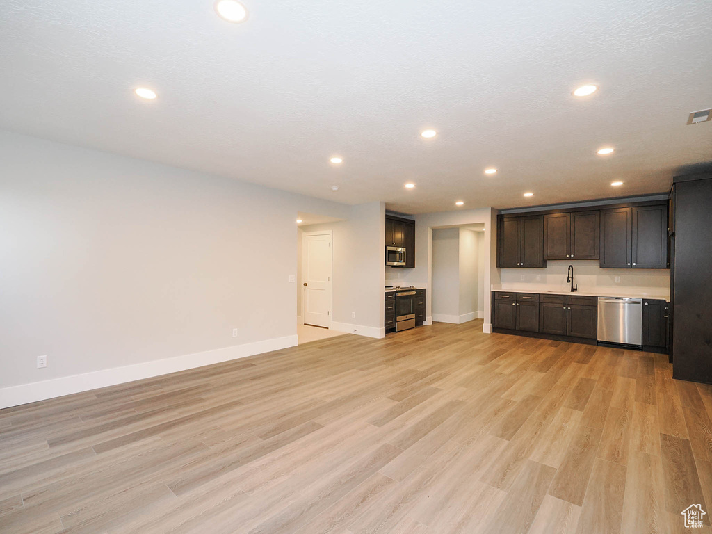 Unfurnished living room with light hardwood / wood-style floors and sink