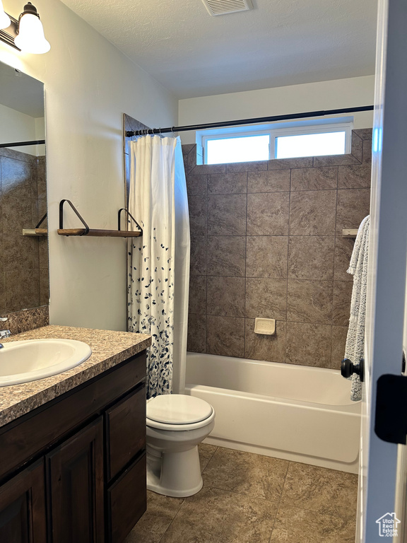 Full bathroom featuring tile floors, toilet, shower / tub combo, and large vanity
