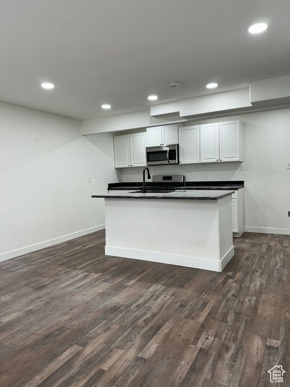 Kitchen featuring white cabinetry, dark hardwood / wood-style flooring, sink, and a kitchen island with sink