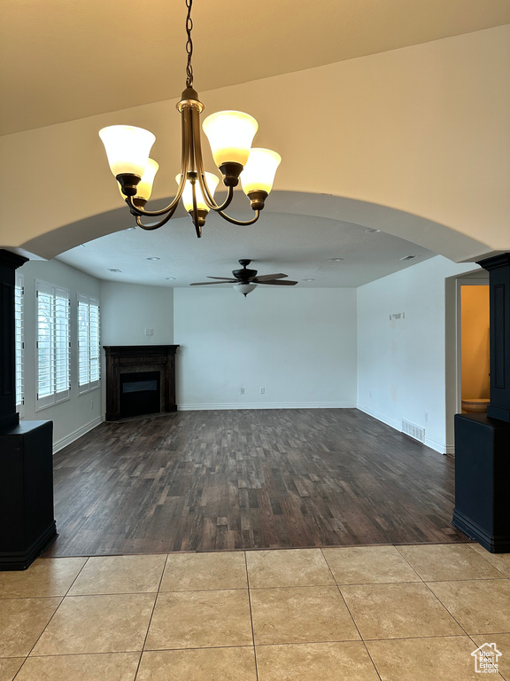 Unfurnished living room with ceiling fan with notable chandelier and hardwood / wood-style floors