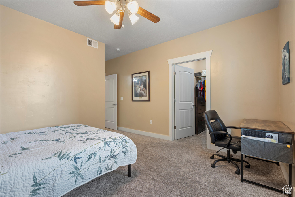 Carpeted bedroom featuring a spacious closet, ceiling fan, and a closet