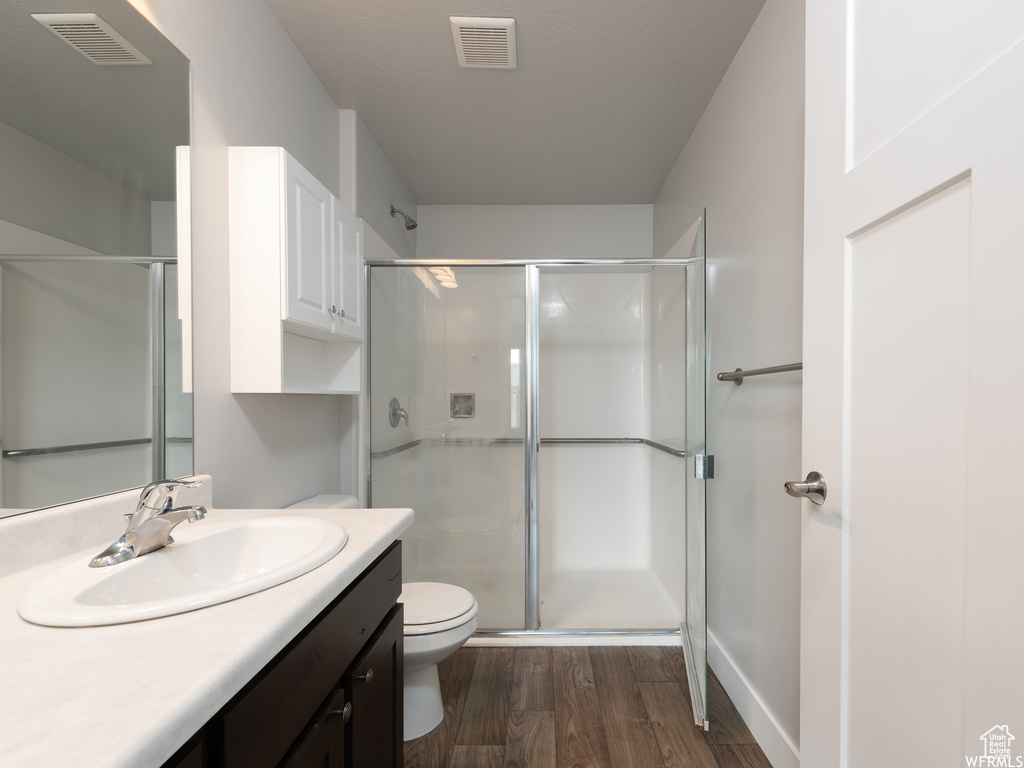 Bathroom featuring vanity, toilet, hardwood / wood-style flooring, and walk in shower