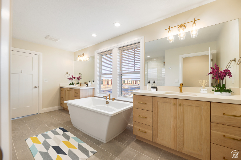 Bathroom with dual vanity, a bathing tub, and tile flooring
