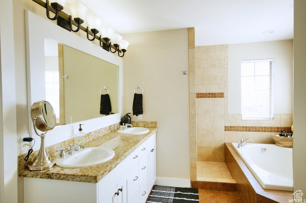 Bathroom with tile floors, tiled bath, and dual bowl vanity