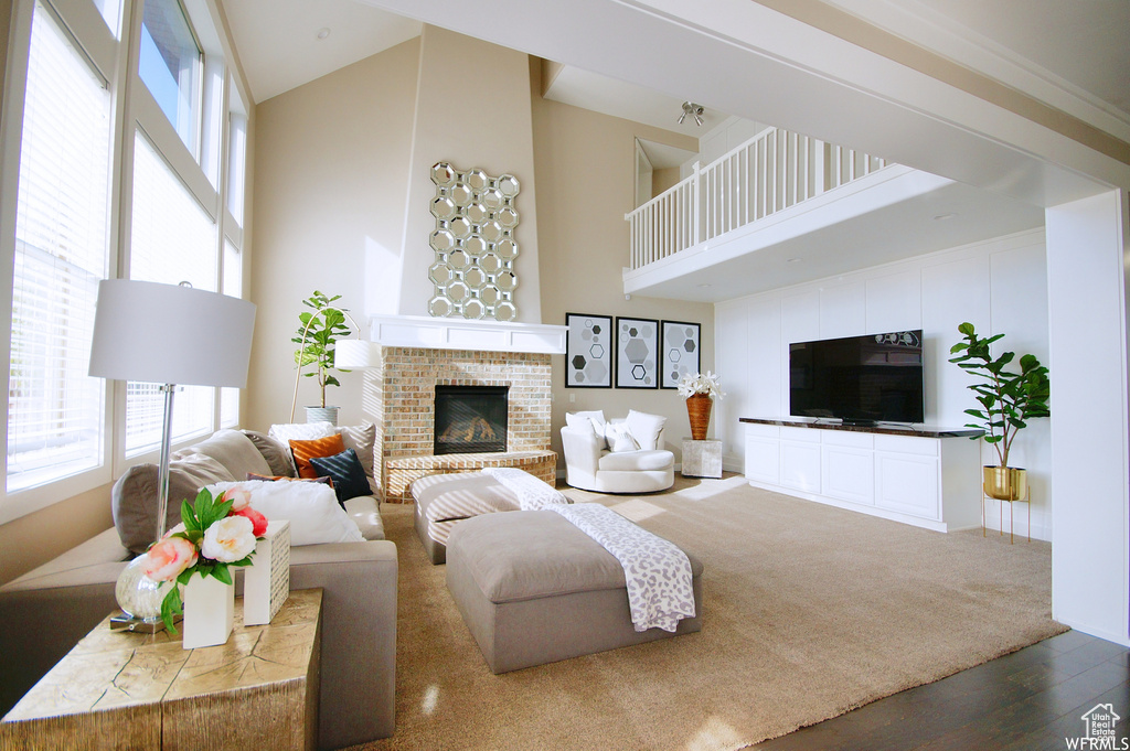 Living room with wood-type flooring, a fireplace, and high vaulted ceiling