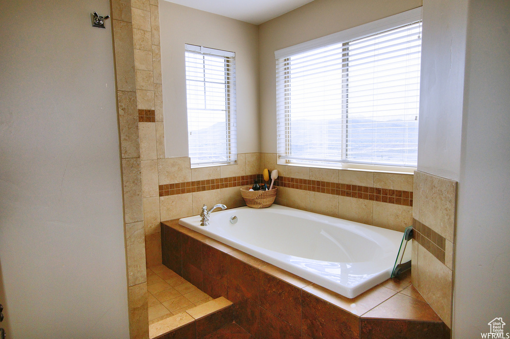 Bathroom with a healthy amount of sunlight and a relaxing tiled bath