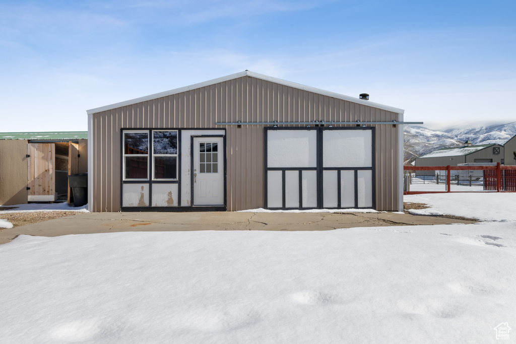 Snow covered property featuring a garage and an outdoor structure