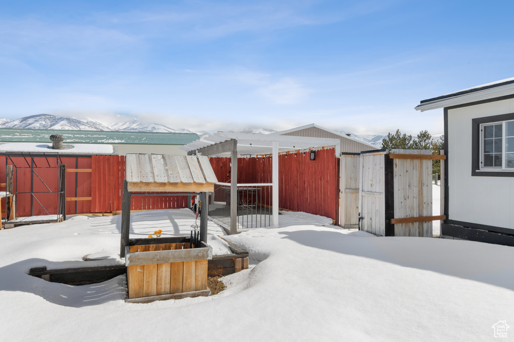 Snow covered patio featuring a mountain view and an outdoor structure