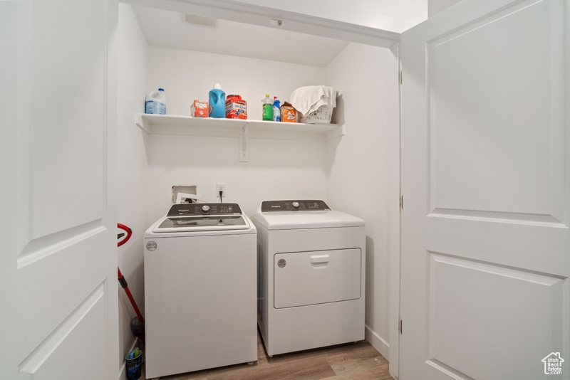 Laundry room with separate washer and dryer, hookup for a washing machine, and light hardwood / wood-style floors