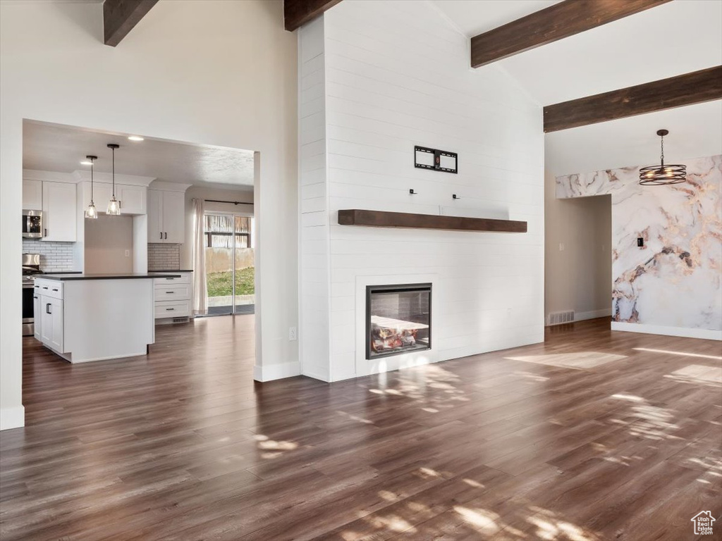 Unfurnished living room featuring high vaulted ceiling, a large fireplace, beamed ceiling, and dark hardwood / wood-style flooring