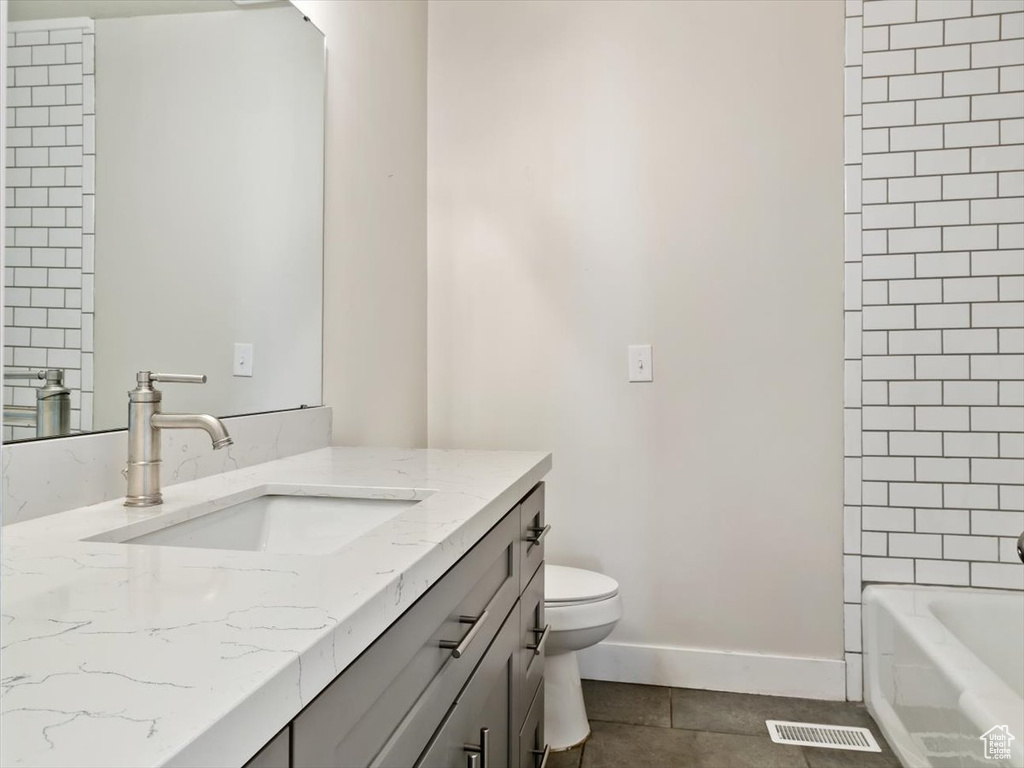 Full bathroom with tile floors, tiled shower / bath combo, toilet, and oversized vanity