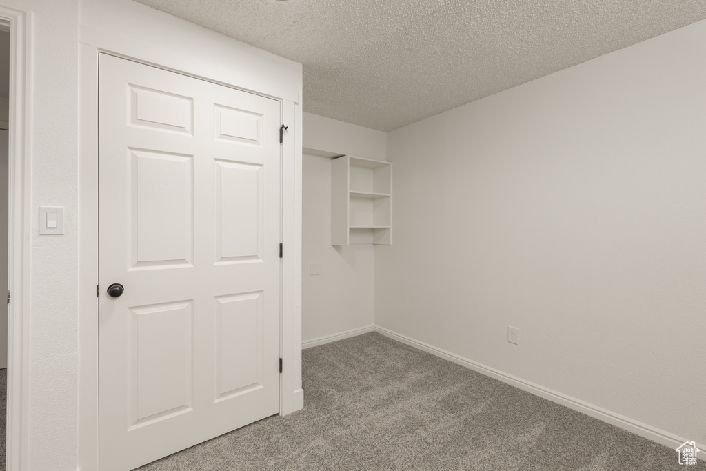 Unfurnished bedroom featuring a textured ceiling, light carpet, and a closet