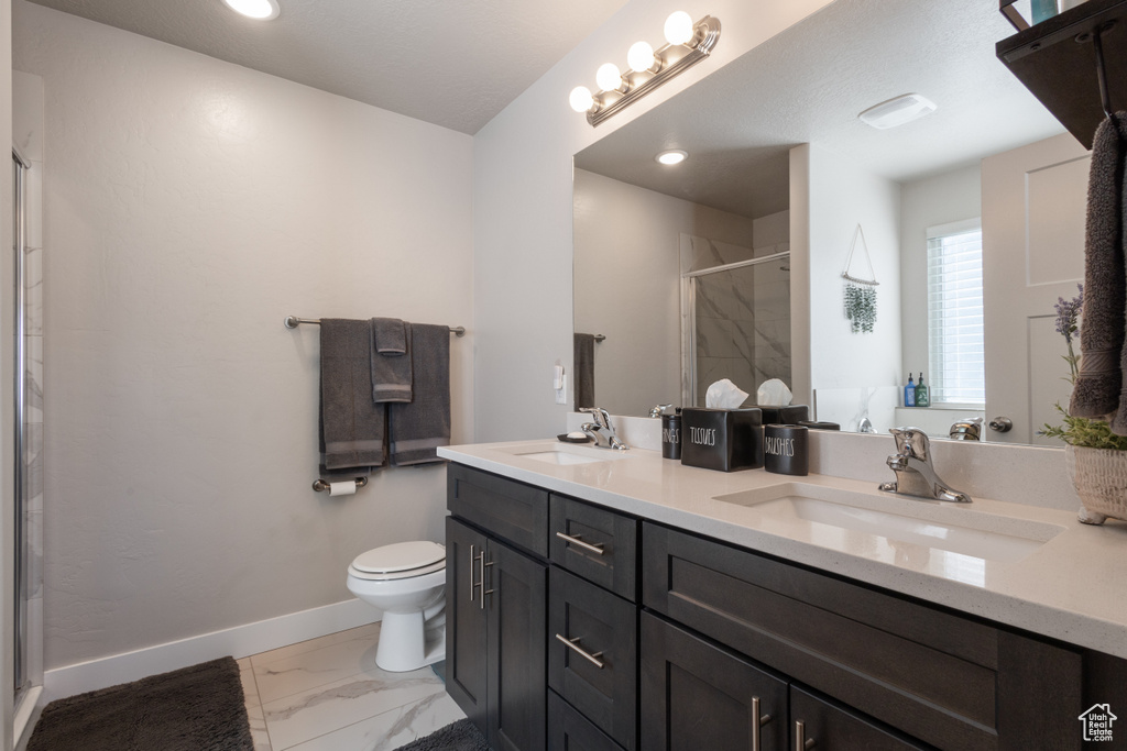 Bathroom featuring dual vanity, toilet, walk in shower, and tile floors