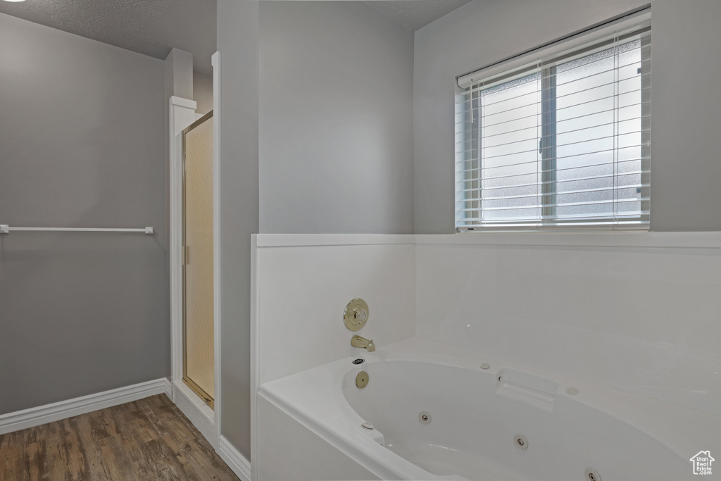 Bathroom with independent shower and bath, a textured ceiling, and hardwood / wood-style floors