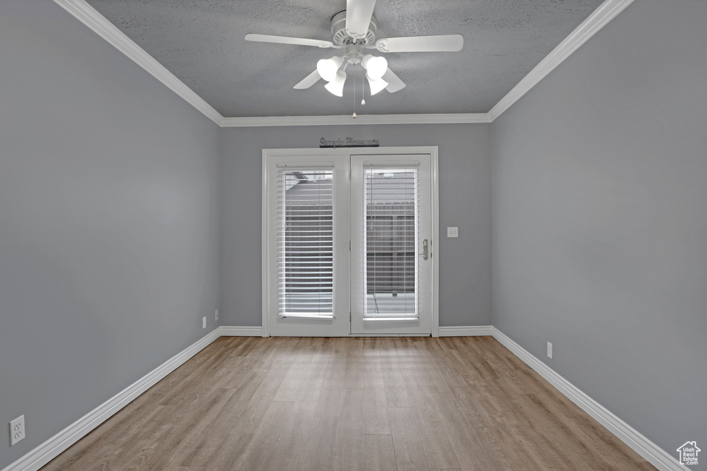 Empty room with a textured ceiling, french doors, ceiling fan, light hardwood / wood-style floors, and crown molding