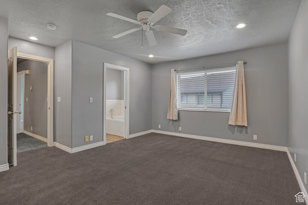 Unfurnished bedroom with ensuite bath, dark carpet, a textured ceiling, and ceiling fan