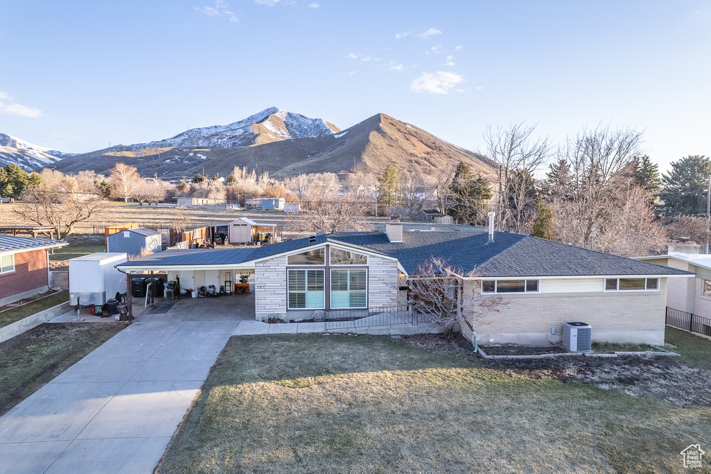 Ranch-style home featuring a mountain view, central air condition unit, and a front yard