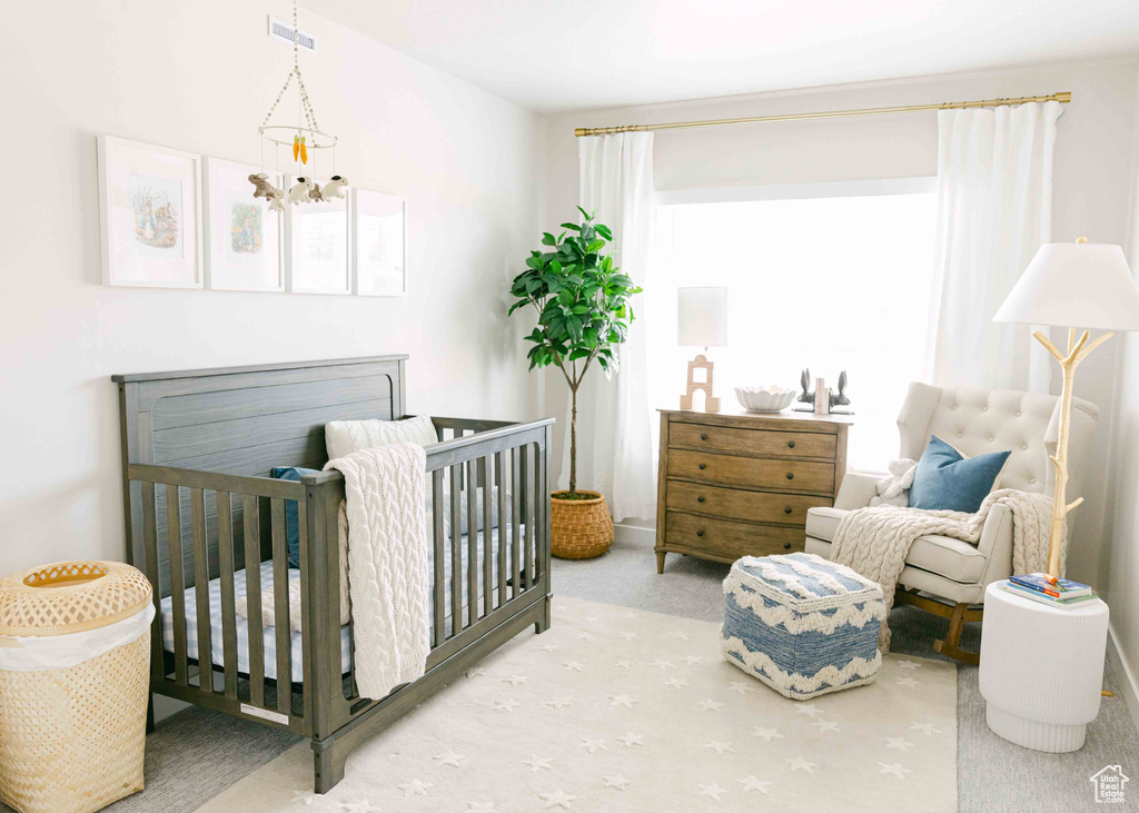 Bedroom featuring an inviting chandelier, light colored carpet, and a nursery area