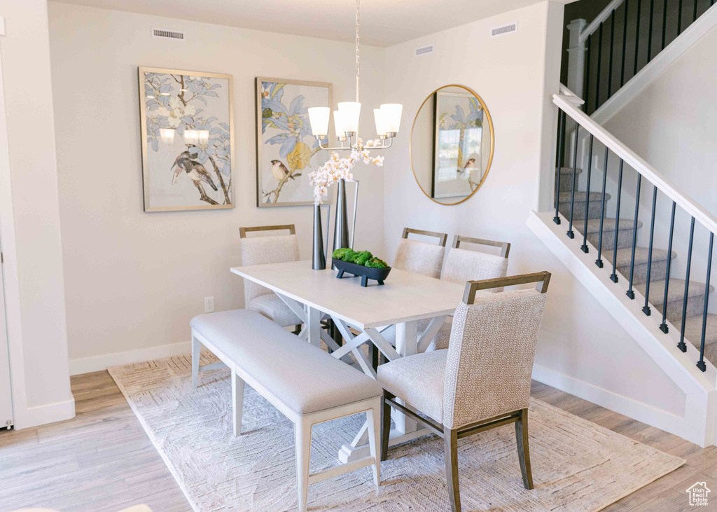 Dining space with a notable chandelier and light hardwood / wood-style floors