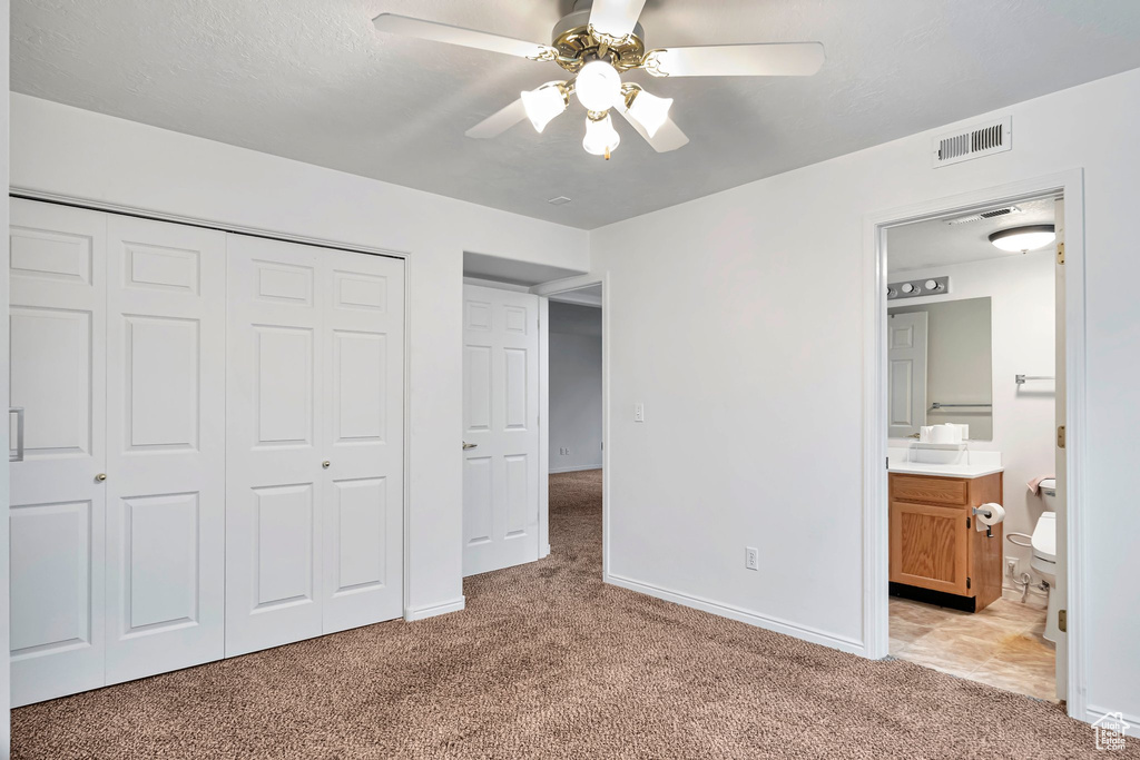 Unfurnished bedroom featuring light colored carpet, ceiling fan, and a closet